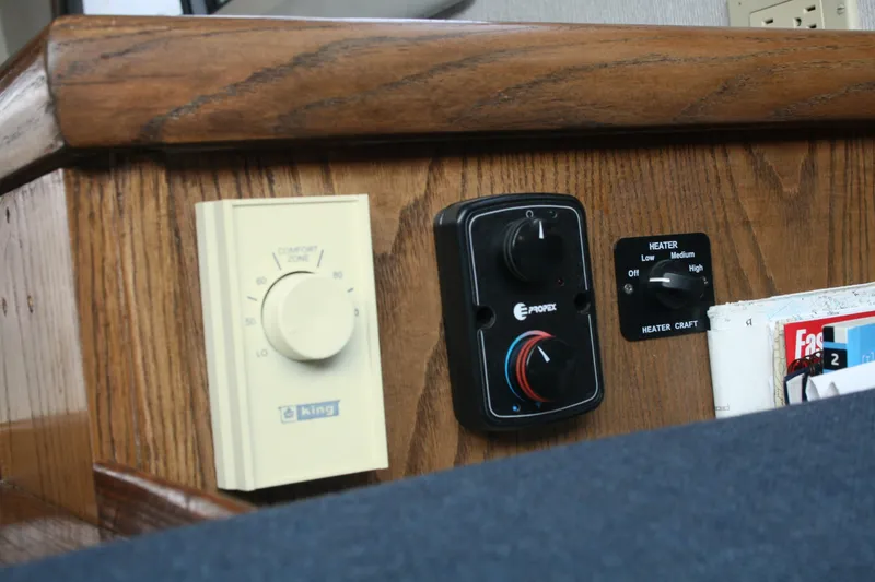 Slide: The Image of 1989 Silverton 34 Convertible boat controls, featuring thermostat and heater settings on wooden panel. - 33