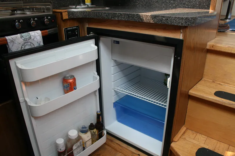 Slide: The Image of Compact refrigerator in 1989 Silverton 34 Convertible boat kitchen, stocked with beverages and condiments. - 19