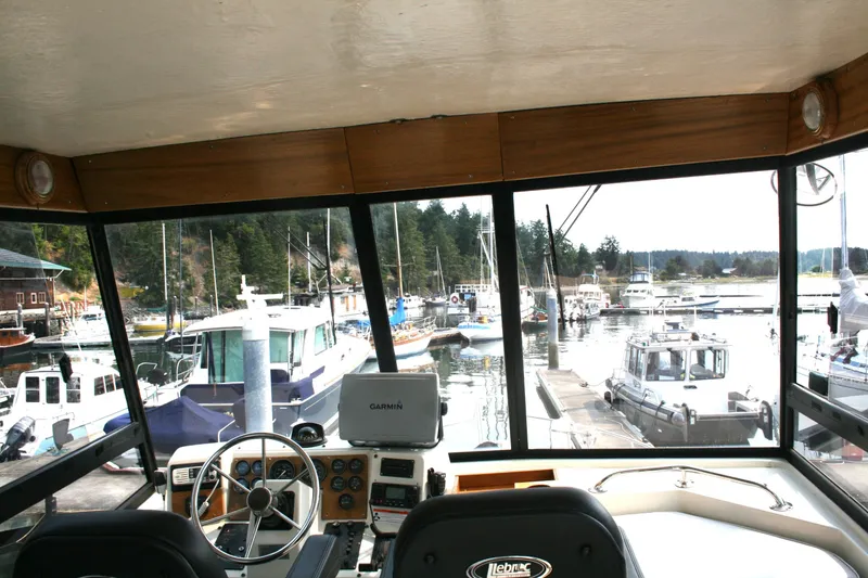 Slide: The Image of Interior view of 1989 Silverton 34 Convertible yacht at marina, showcasing helm and docked boats. - 7
