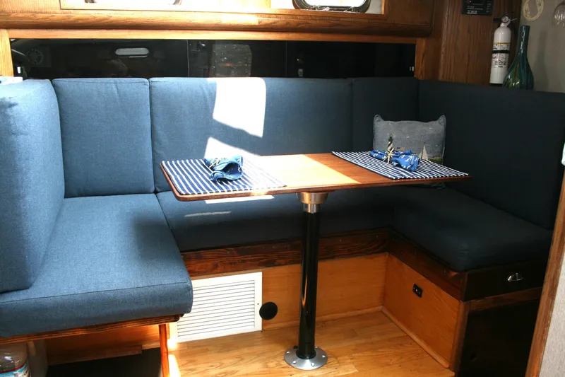 Slide: The Image of Cozy dining area in 1989 Silverton 34 Convertible boat with blue seating and wooden table. - 15