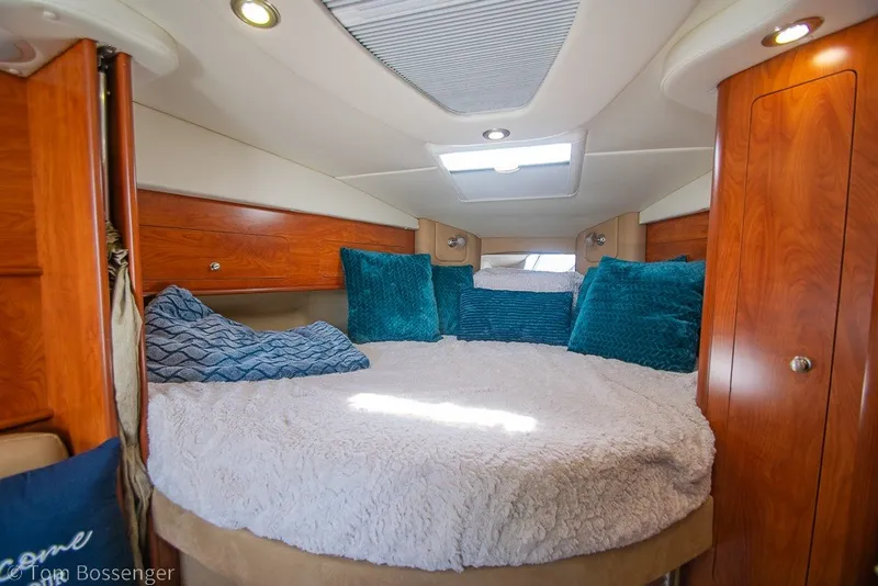 Slide: The Image of Luxurious cabin interior of 2012 Rinker 310 Express Cruiser with plush bedding and wood accents. - 16