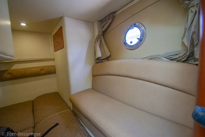 Slide: The Image of Interior cabin of 2012 Rinker 310 Express Cruiser with beige seating and porthole window. - 24