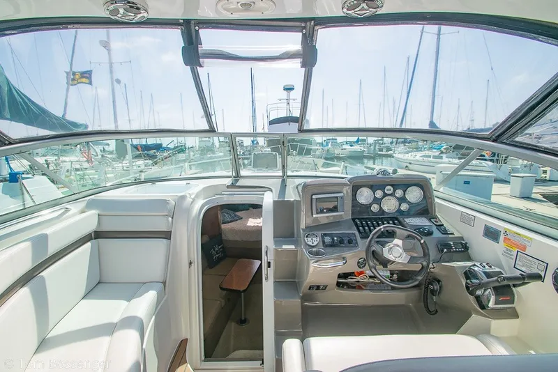 Slide: The Image of 2012 Rinker 310 Express Cruiser cockpit with marina view, featuring modern controls and seating. - 31
