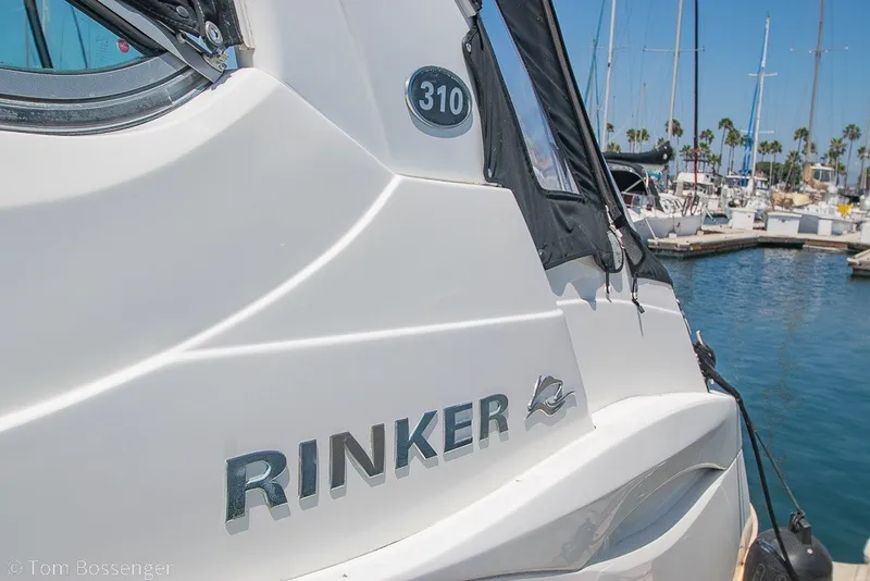 Slide: The Image of 2012 Rinker 310 Express Cruiser docked at a marina, sunny day. - 7