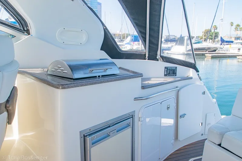 Slide: The Image of 2012 Rinker 310 Express Cruiser interior with grill and storage, docked at marina. - 36