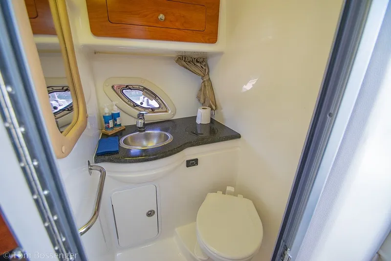 Slide: The Image of 2012 Rinker 310 Express Cruiser bathroom with sink, toilet, and storage cabinet. - 23