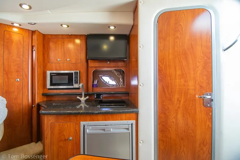Slide: The Image of Interior of 2012 Rinker 310 Express Cruiser with kitchenette and wood finish. - 19