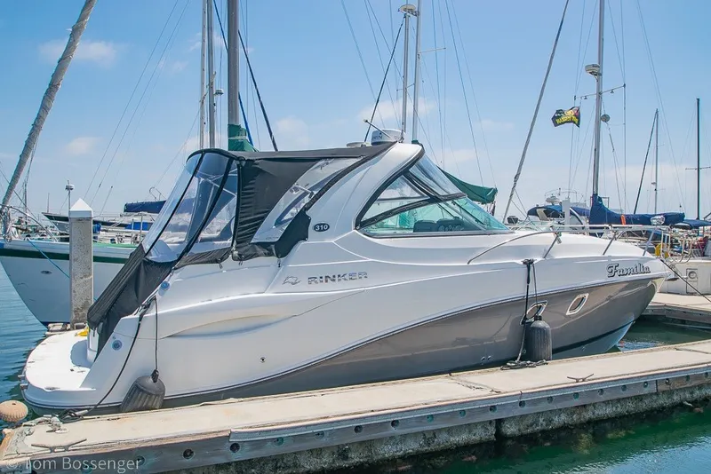 Slide: The Image of 2012 Rinker 310 Express Cruiser docked at marina under clear blue sky. - 2