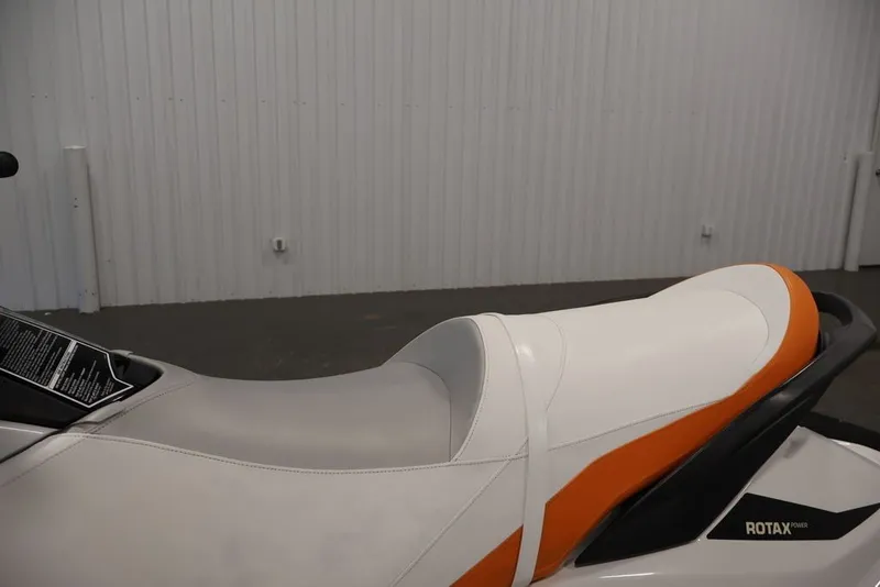 Slide: The Image of 2014 Sea-Doo GTI 130 jet ski seat with orange and white design in a garage. - 14