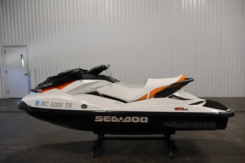 Slide: The Image of 2014 Sea-Doo GTI 130 jet ski in a showroom, featuring sleek white and orange design. - 7