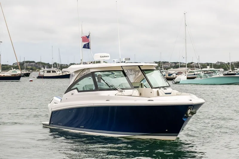 Slide: The Image of 2024 Tiara Yachts 34 LX cruising in a scenic harbor with other boats. - 4
