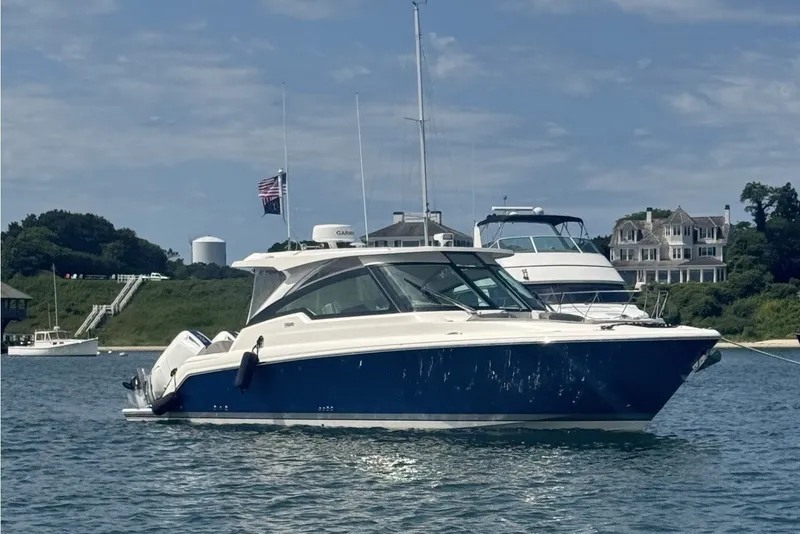The Image of A 2024 Tiara Yachts 34 LX is anchored on the water. Houses are visible in the background. - 0