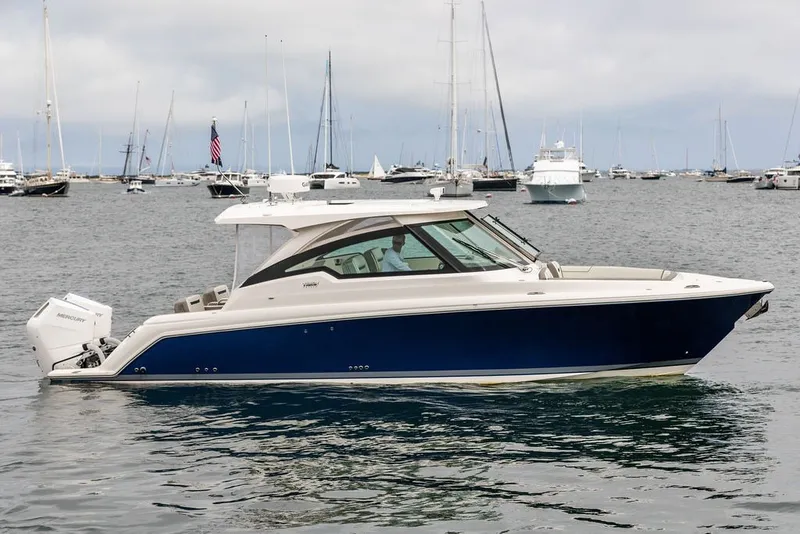 The Image of 2024 Tiara Yachts 34 LX in marina, sleek design, blue hull, outboard engines. - 0