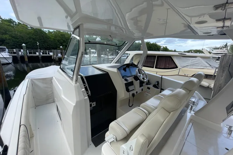 Slide: The Image of 2022 Regal 33 SAV boat interior with helm, steering wheel, and seating at a marina. - 14