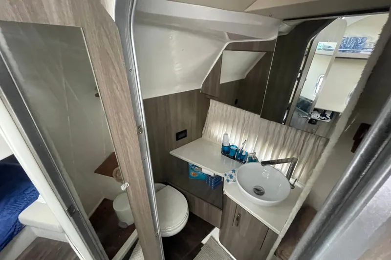 Slide: The Image of 2022 Regal 33 SAV boat bathroom with modern sink, mirror, and wooden cabinetry. - 25