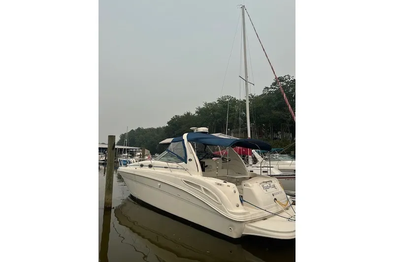 The Image of 2002 Sea Ray 360 Sundancer yacht docked at marina, featuring sleek design and blue canopy. - 0