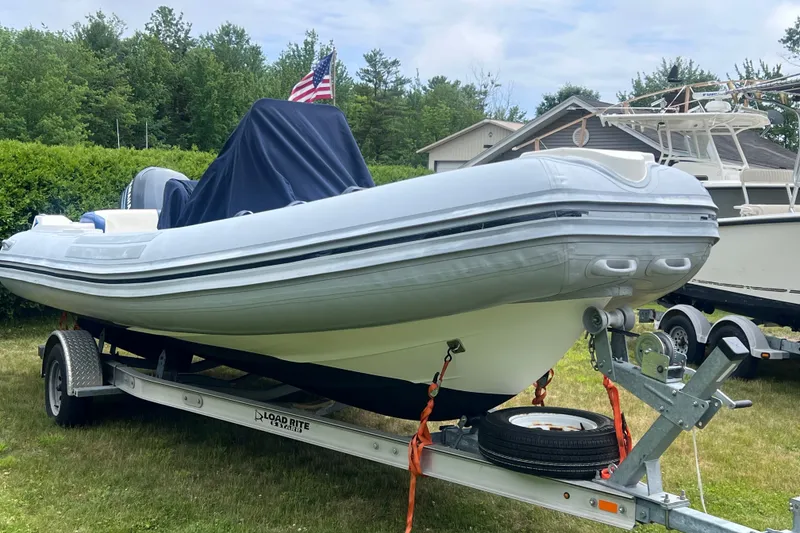 Slide: The Image of 2003 Nautica 22 Wide Body boat on trailer, covered, with American flag in background. - 7