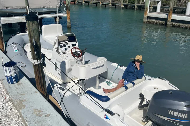Slide: The Image of 2003 Nautica 22 Wide Body boat docked, person relaxing onboard, Yamaha engine visible. - 11