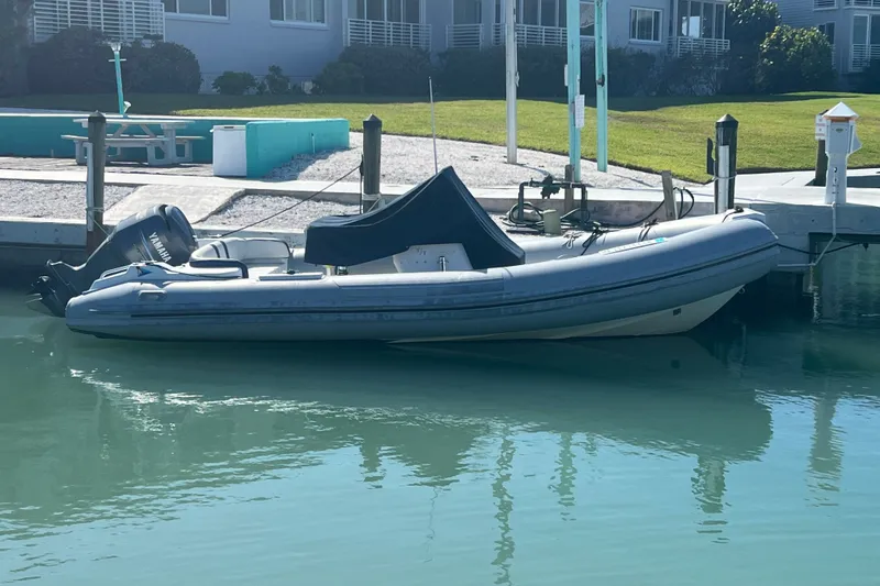 The Image of 2003 Nautica 22 Wide Body boat docked in calm waters near residential area. - 9