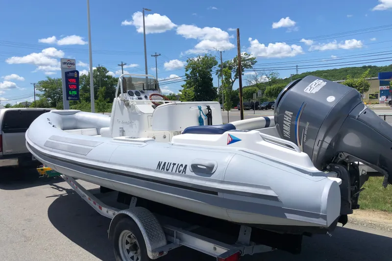 Slide: The Image of 2003 Nautica 22 Wide Body boat on trailer with Yamaha engine, parked near gas station. - 14