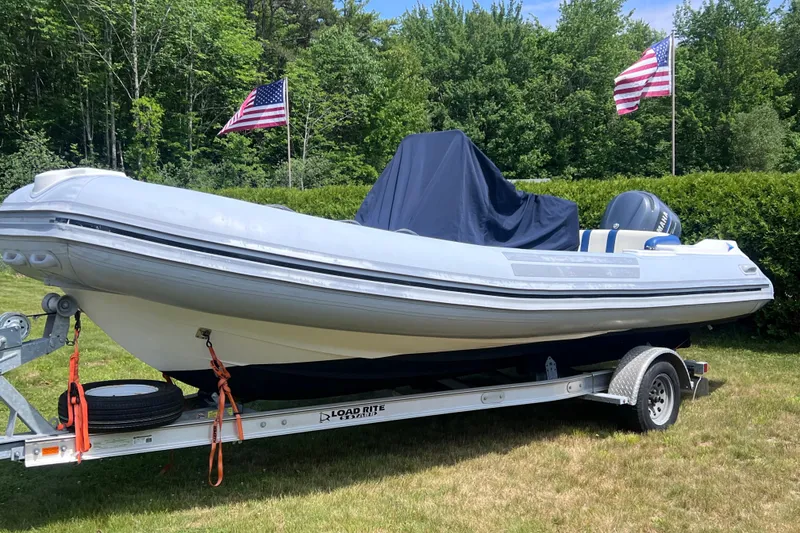 Slide: The Image of 2003 Nautica 22 Wide Body boat on trailer with American flags in background. - 1