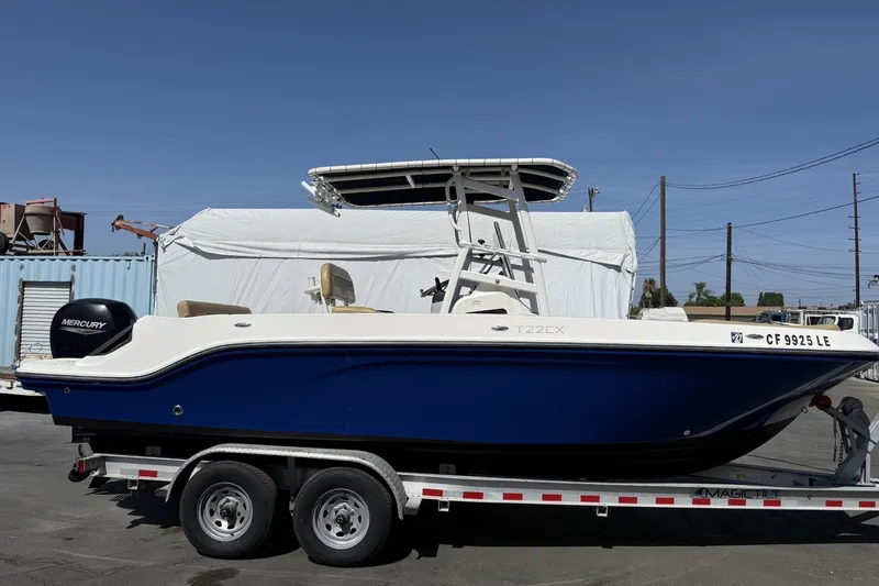 Slide: The Image of 2022 Bayliner Trophy T22CX boat on trailer, featuring a sleek blue hull and Mercury engine. - 2