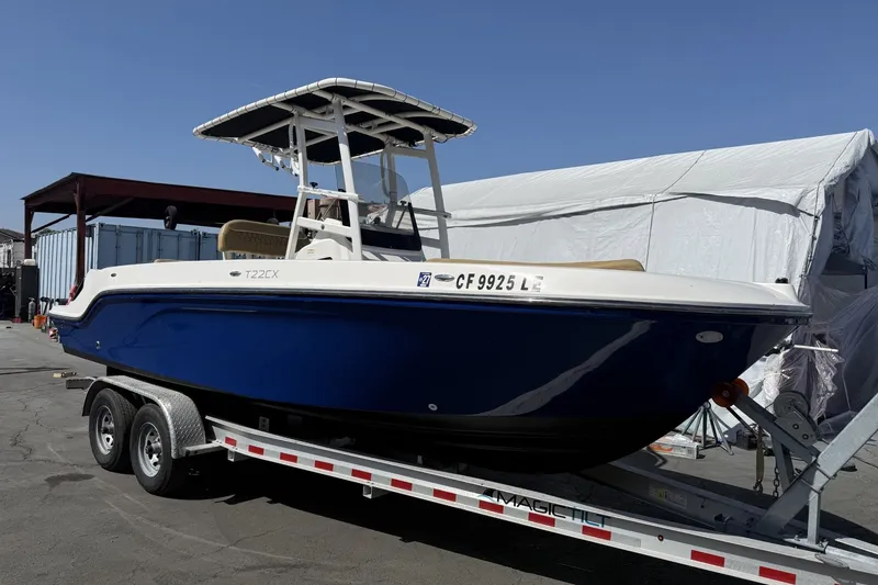 Slide: The Image of 2022 Bayliner Trophy T22CX boat on trailer, blue hull, parked outdoors. - 3