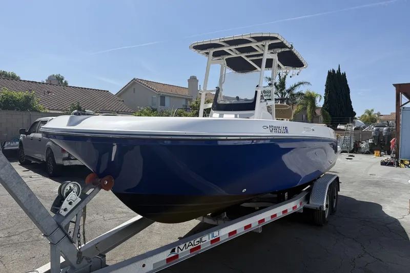 Slide: The Image of 2022 Bayliner Trophy T22CX boat on trailer in sunny residential area. - 4