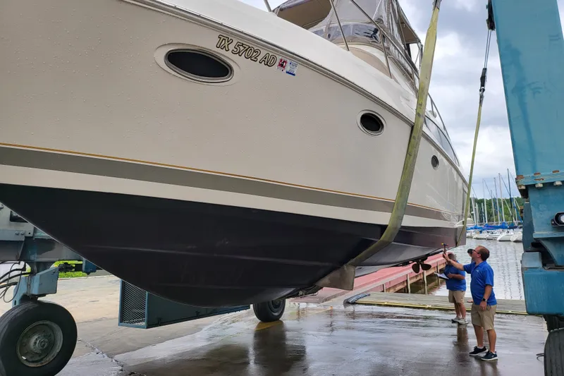 Slide: The Image of 2001 Regal Commodore 3780 yacht being lifted at a marina with two people observing. - 3