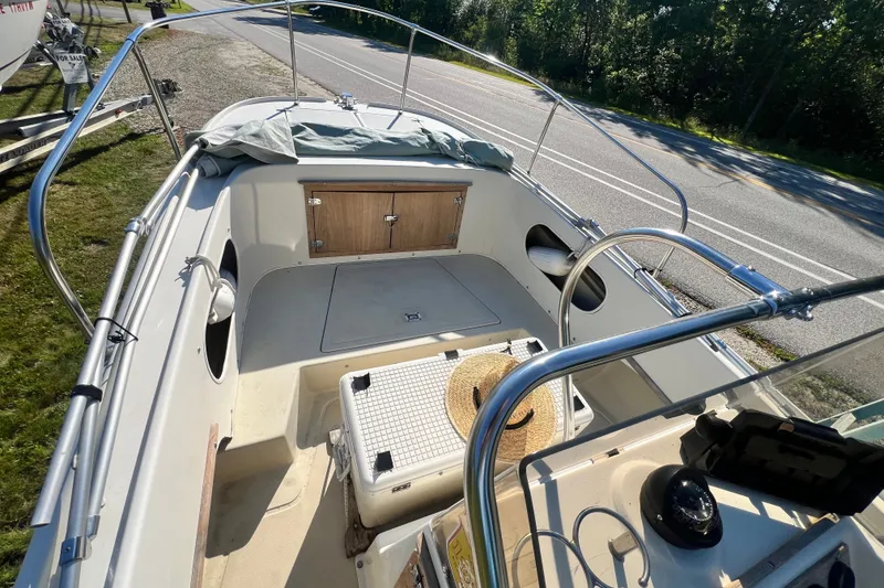 Slide: The Image of 1973 Boston Whaler 19 OUTRAGE boat interior with seating and steering wheel, parked roadside. - 3