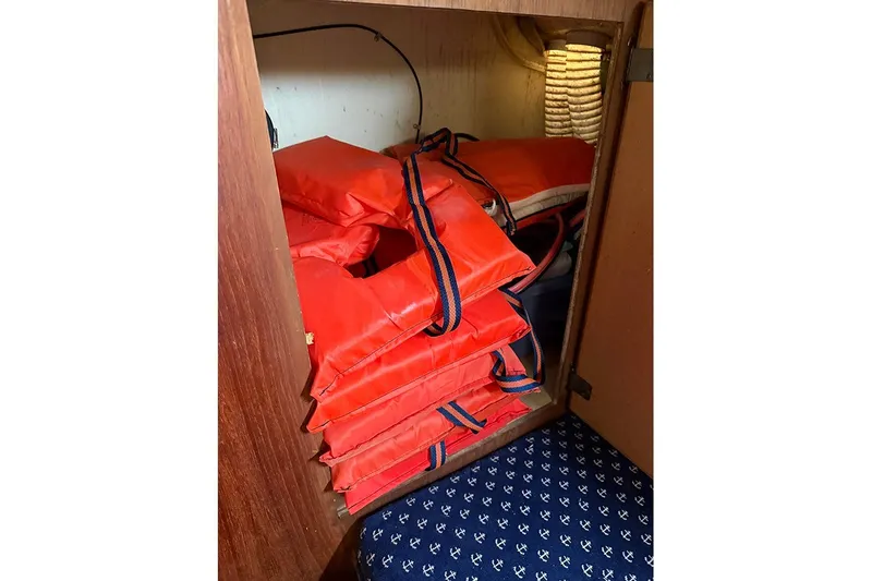Slide: The Image of Orange life jackets stored in a wooden cabinet on a 1983 S2 9.2C sailboat. - 19
