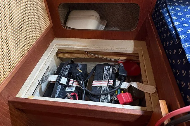 Slide: The Image of Battery compartment of a 1983 S2 9.2C sailboat, featuring dual batteries and wooden paneling. - 15