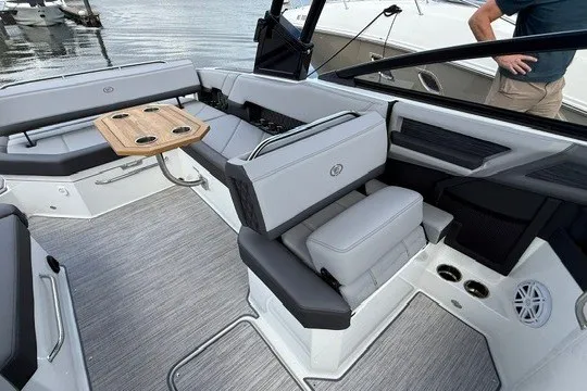 Slide: The Image of 2024 Cobalt R8 boat interior with gray seating and wooden table on a lake. - 8