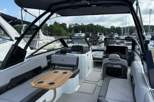 Slide: The Image of 2024 Cobalt R8 boat interior with seating, table, and helm at marina. - 5