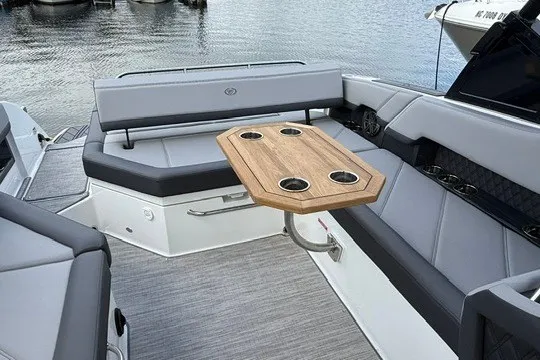 Slide: The Image of 2024 Cobalt R8 boat interior with gray seating and wooden table, docked by the water. - 11