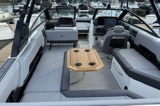 Slide: The Image of 2024 Cobalt R8 boat interior with sleek seating and wooden table, docked at a marina. - 7