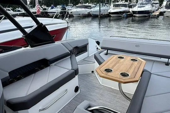 Slide: The Image of 2024 Cobalt R8 boat interior with seating and wooden table, docked at a marina. - 12