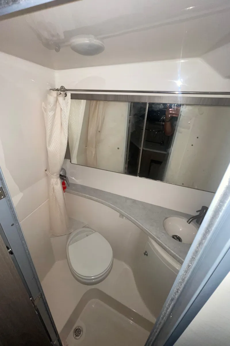 Slide: The Image of 2019 Regal 28 Express boat bathroom with toilet, sink, and mirror. - 10