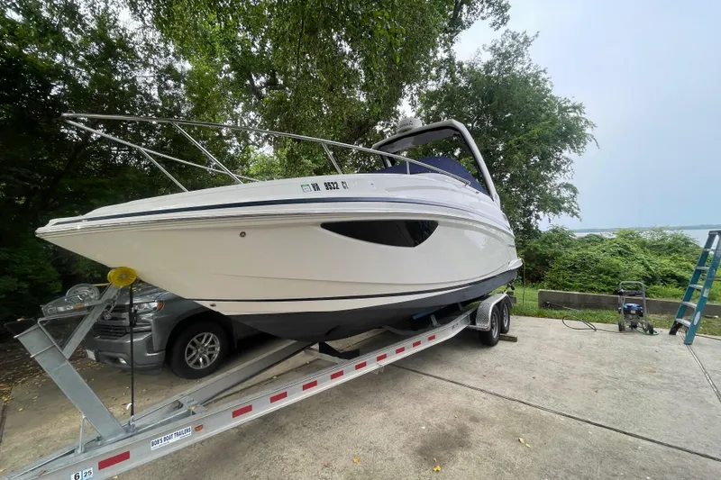 Slide: The Image of 2019 Regal 28 Express boat on trailer, parked outdoors near trees. - 2