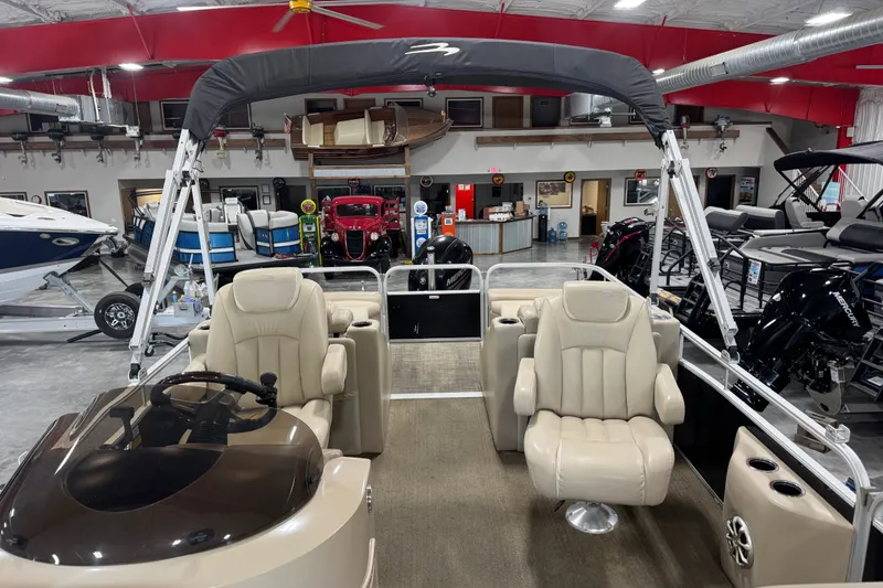 Slide: The Image of 2013 Bennington 2375 GCW pontoon boat interior with beige seating in a showroom. - 10