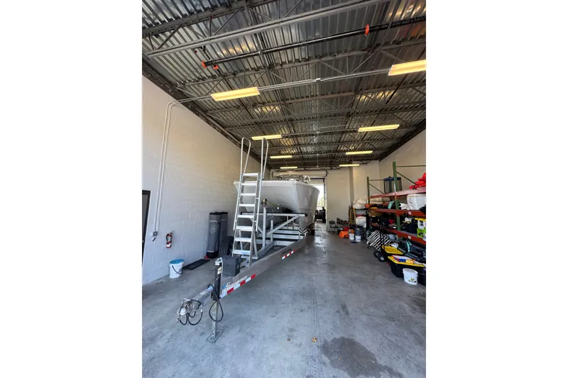 Slide: The Image of 2023 Freeman 37 boat on trailer in a spacious garage with equipment shelves. - 49