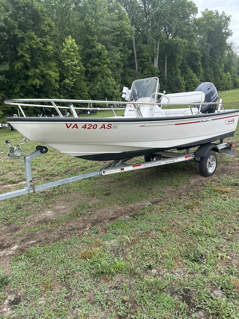 The Image of A 1997 Boston Whaler DAUNTLESS on a trailer, surrounded by trees and grass. - 1