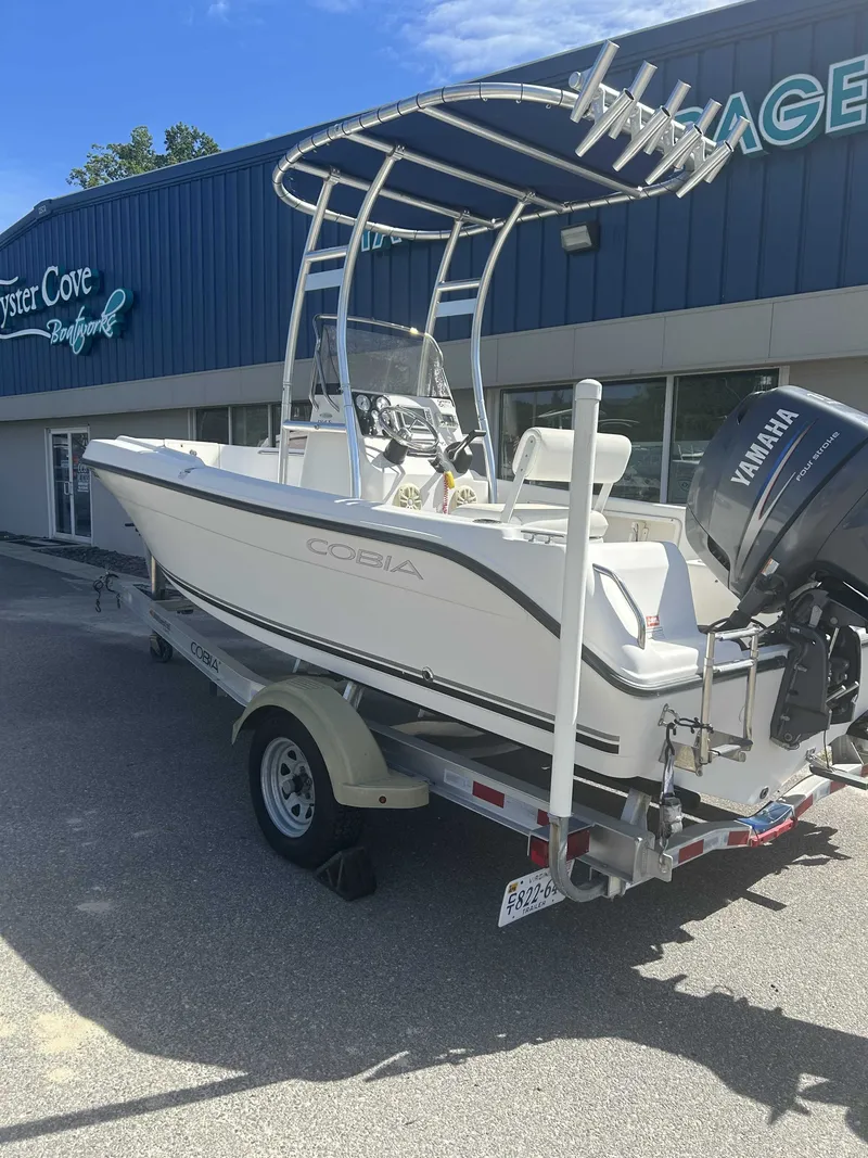 The Image of A white 2010 Cobia 194SE boat on a trailer in front of a building. - 1