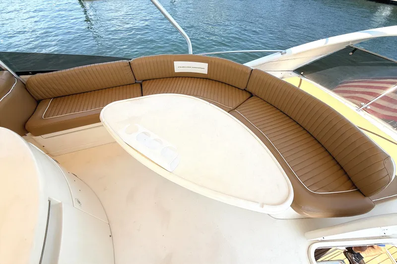 Slide: The Image of The 2000 Fairline Squadron 55 features an elegant, curved seating area with brown upholstery. - 26