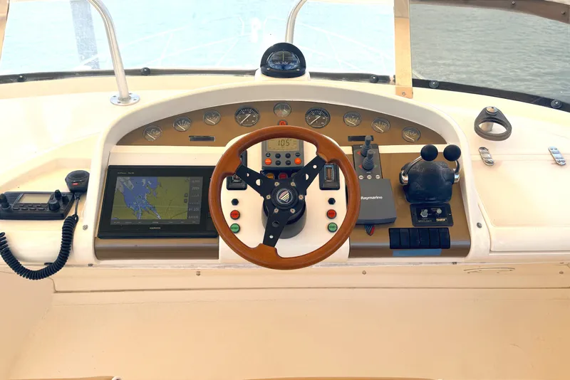 Slide: The Image of The image shows the helm of a 2000 Fairline Squadron 55 with a wooden steering wheel and navigation system. - 21