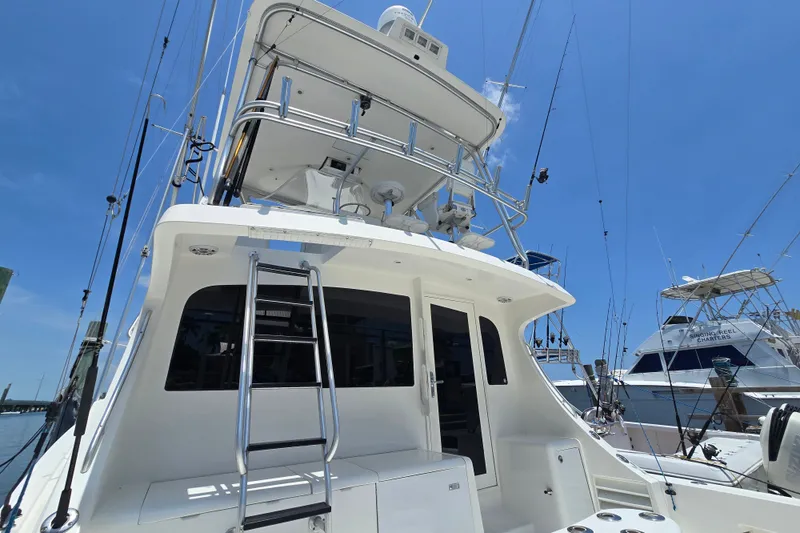 Slide: The Image of 2005 Cavileer 44 Convertible yacht with ladder and fishing rods, docked under clear blue sky. - 36