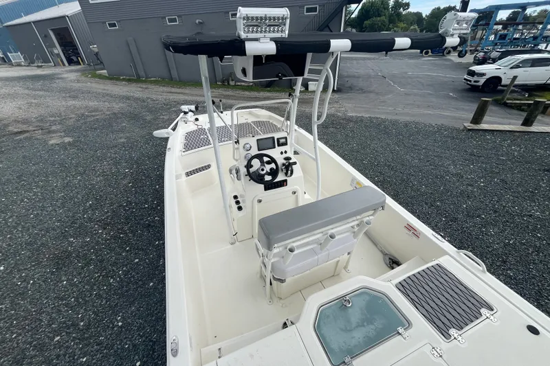 Slide: The Image of 2024 Mako Pro Skiff 19 CC boat with center console and seating, parked outdoors. - 14