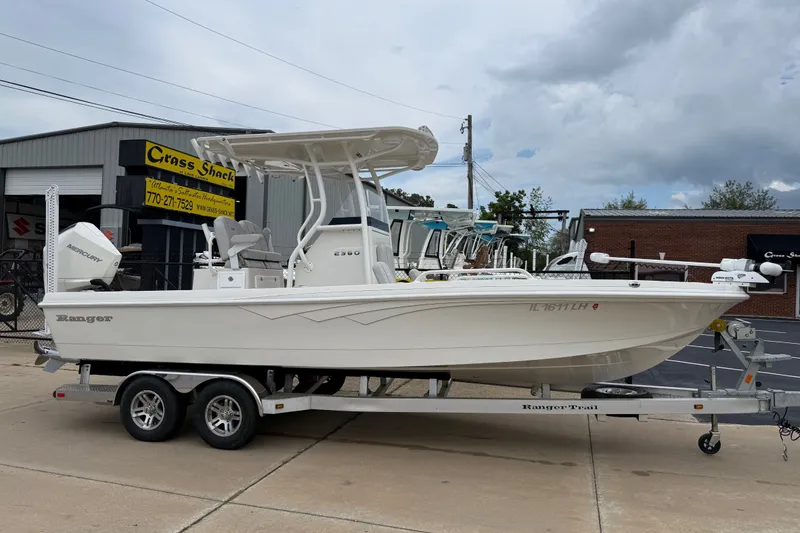 Slide: The Image of 2024 Ranger 2360 Bay boat on trailer, parked outside dealership under cloudy sky. - 12