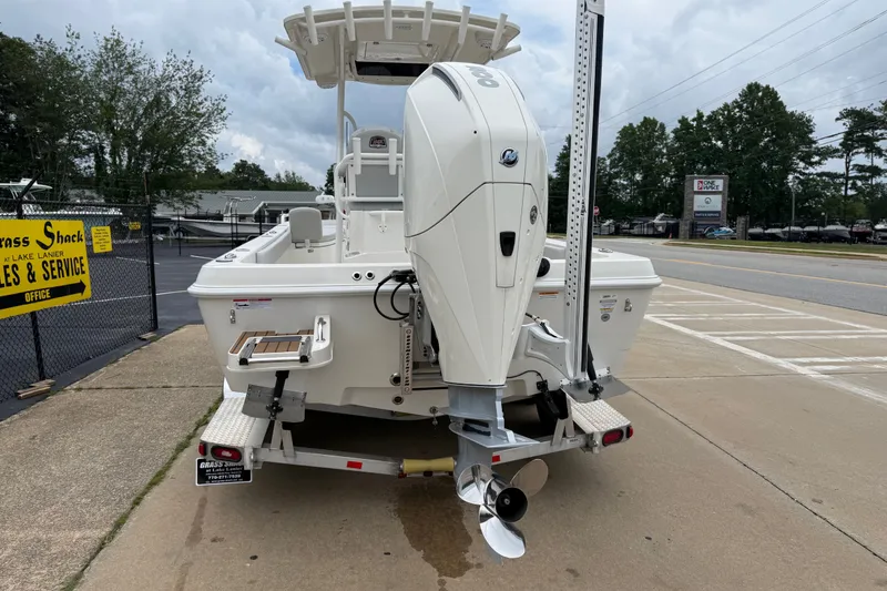 Slide: The Image of 2024 Ranger 2360 Bay boat with powerful outboard motor, parked near sales and service area. - 13