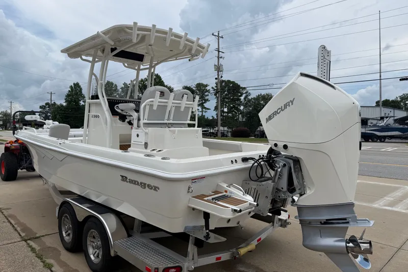 Slide: The Image of 2024 Ranger 2360 Bay boat with Mercury engine on a trailer, parked outdoors. - 15